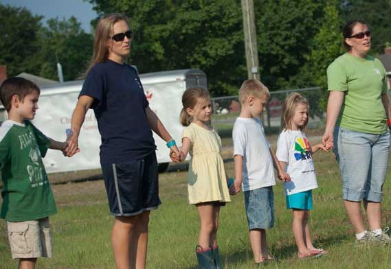 People standing in a field holding hands